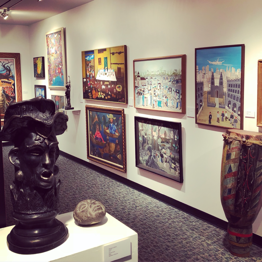 This photograph displays several artworks as displayed at The Art Galleries at Ramapo College of New Jersey. The collection of works we will digitize ranges in scale and format, including sculpture, painting, and mixed-media works. Currently, the majority of the Haitian art collection is within limited storage facilities adjacent to the galleries in the Berrie Center for Performing and Visual Arts. More information on the collection is available at: https://www.ramapo.edu/berriecenter/art-galleries/selden-rodman
